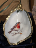 Decorative shell with a painted bird on a branch, gold rim, and blue fabric background