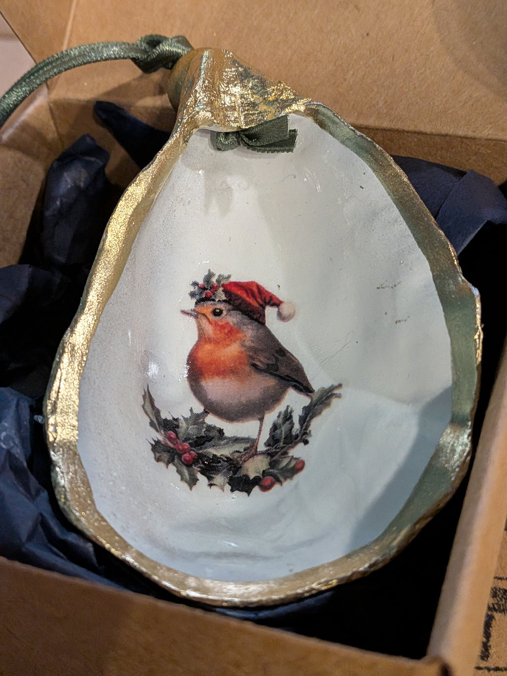 Decorative shell with a painted robin wearing a Santa hat on a white background.