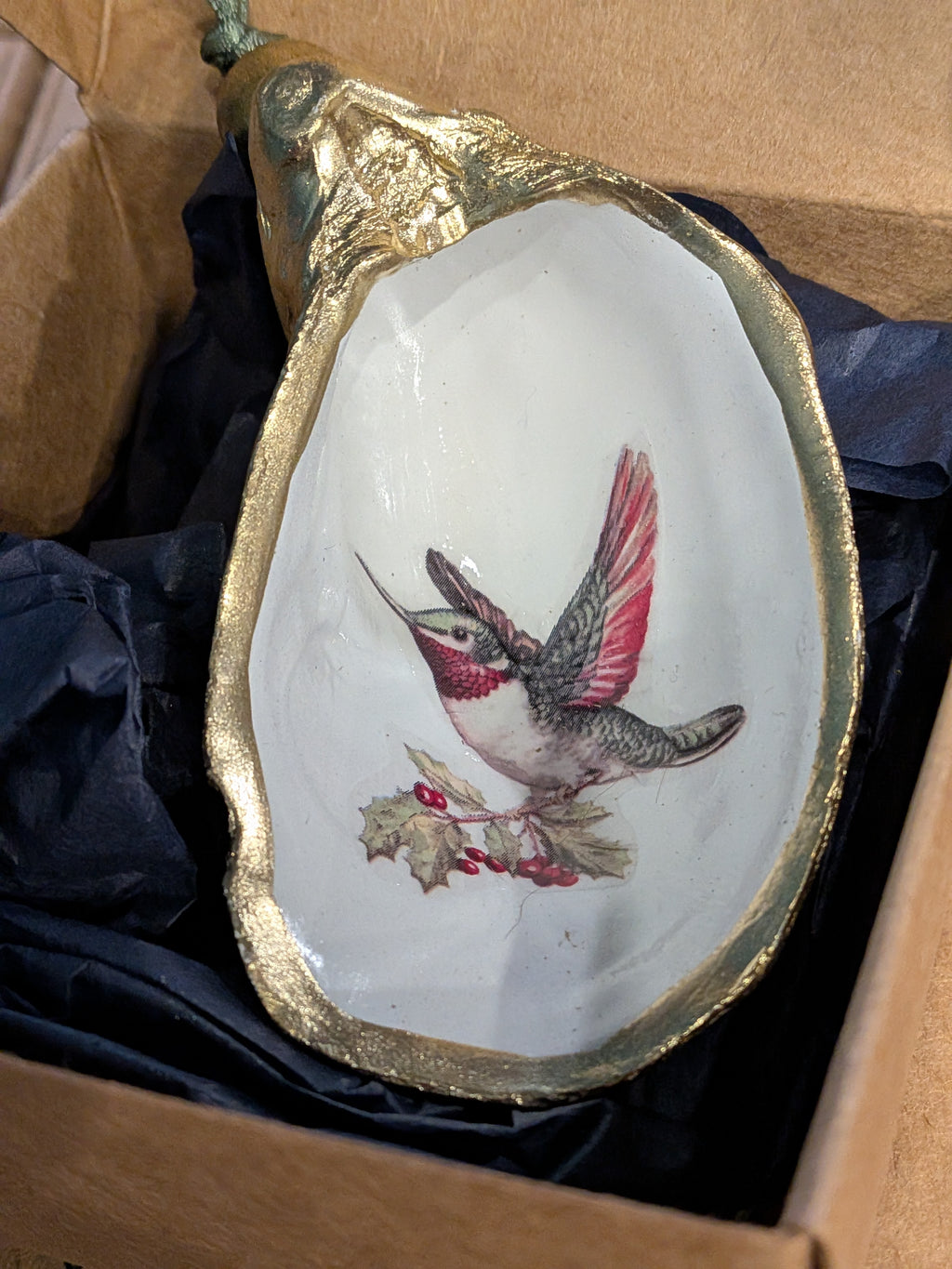 Decorative dish with a gold rim and bird illustration on a black fabric background