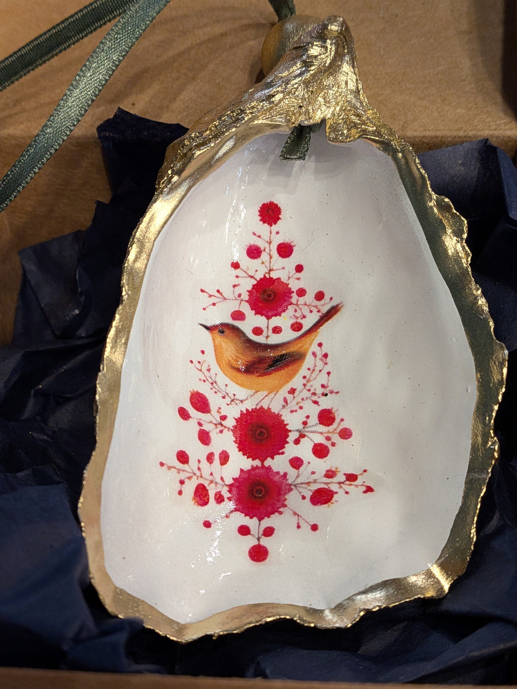 Decorative shell with gold rim, red floral design, and bird illustration on a dark fabric background.